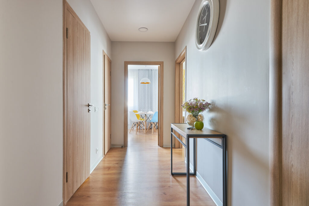 Heller Wohnungsflur mit Innentüren in Holzoptik, Holzfußboden und dunklem Konsolentisch